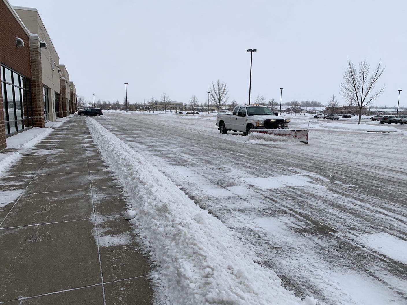 Plow truck clearing snow from a commercial parking lot in Minnesota